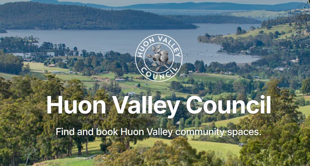 A scenic view of Huon Valley features rolling hills, scattered trees, and water bodies under a blue sky. The Huon Valley Council logo is at the top. Text reads, Huon Valley Council: Find and book Huon Valley community spaces.